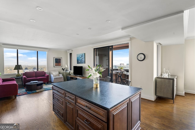 kitchen featuring dark wood-type flooring, dark countertops, open floor plan, and a center island