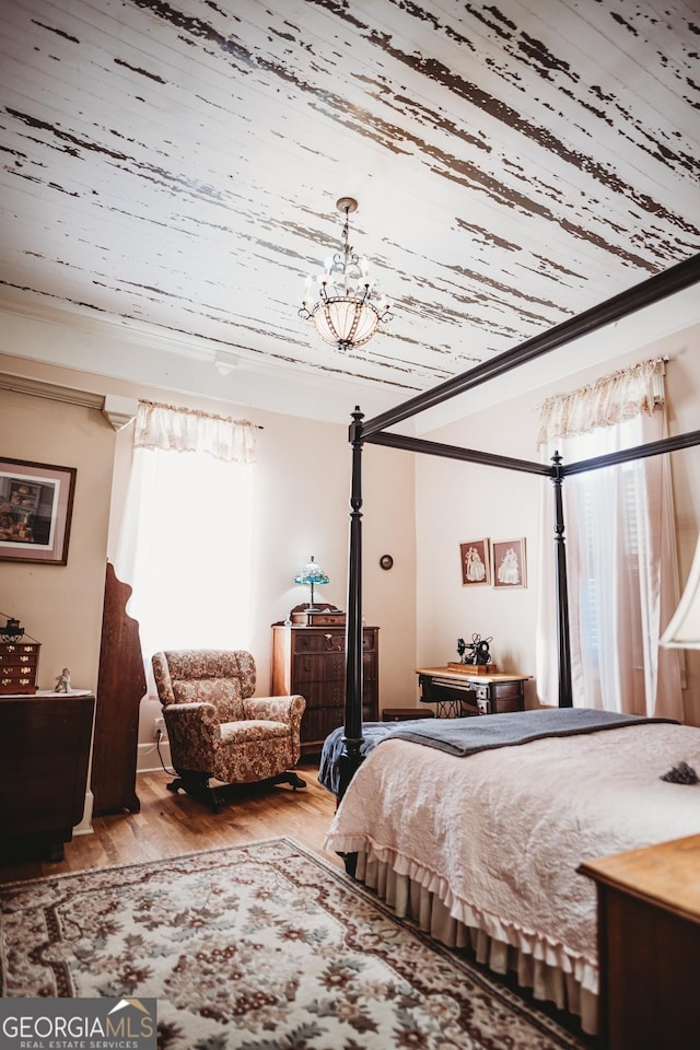 bedroom with crown molding, a notable chandelier, and hardwood / wood-style flooring