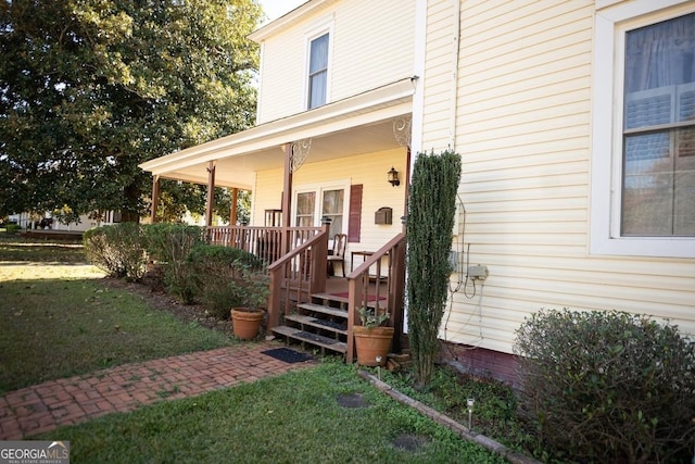 property entrance with covered porch and a yard