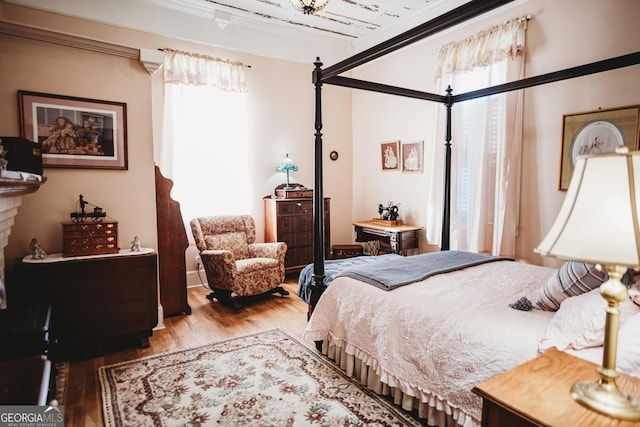 bedroom with multiple windows, crown molding, and hardwood / wood-style flooring