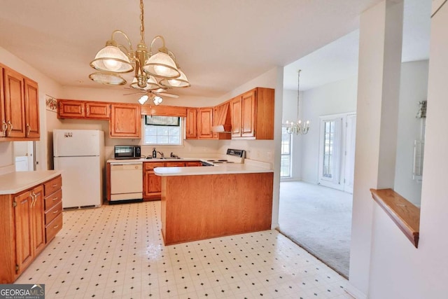 kitchen with white appliances, sink, ceiling fan with notable chandelier, kitchen peninsula, and light colored carpet