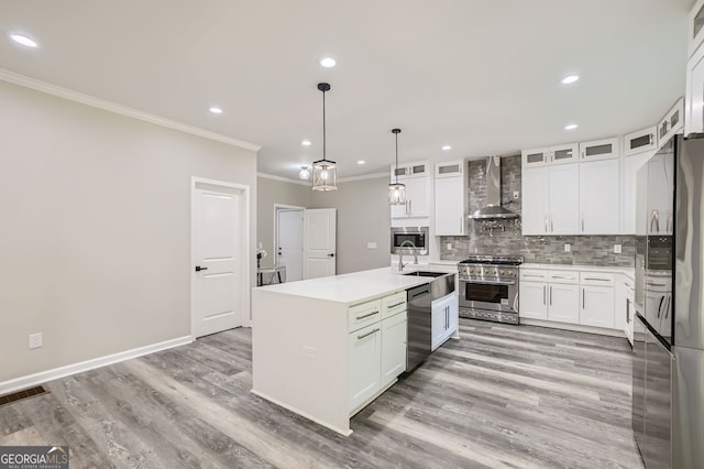 kitchen featuring a center island with sink, stainless steel appliances, white cabinets, wall chimney exhaust hood, and light hardwood / wood-style flooring