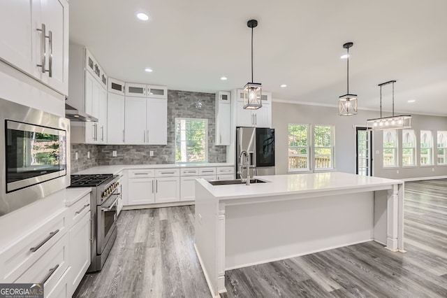 kitchen featuring white cabinets, decorative light fixtures, an island with sink, and stainless steel appliances