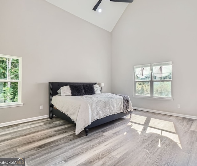 bedroom featuring high vaulted ceiling, hardwood / wood-style floors, multiple windows, and ceiling fan