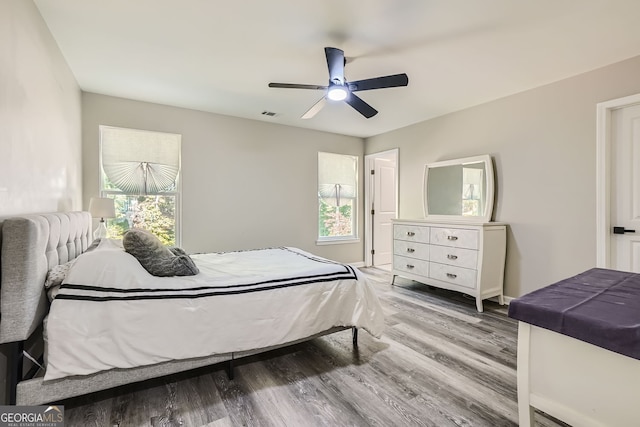 bedroom featuring multiple windows, hardwood / wood-style floors, and ceiling fan