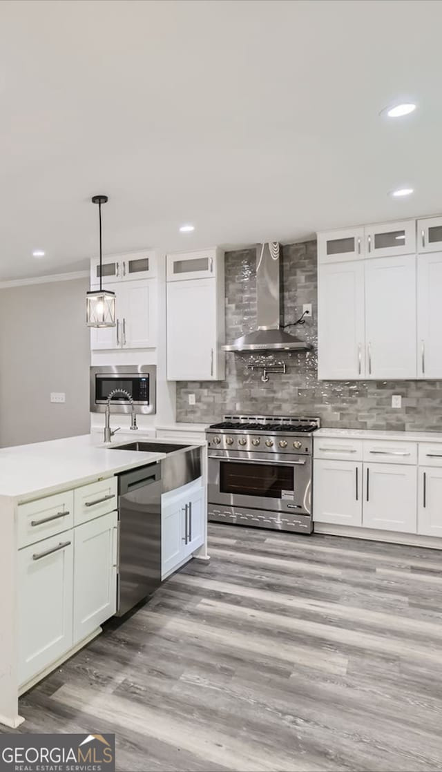 kitchen featuring appliances with stainless steel finishes, wall chimney exhaust hood, and white cabinets