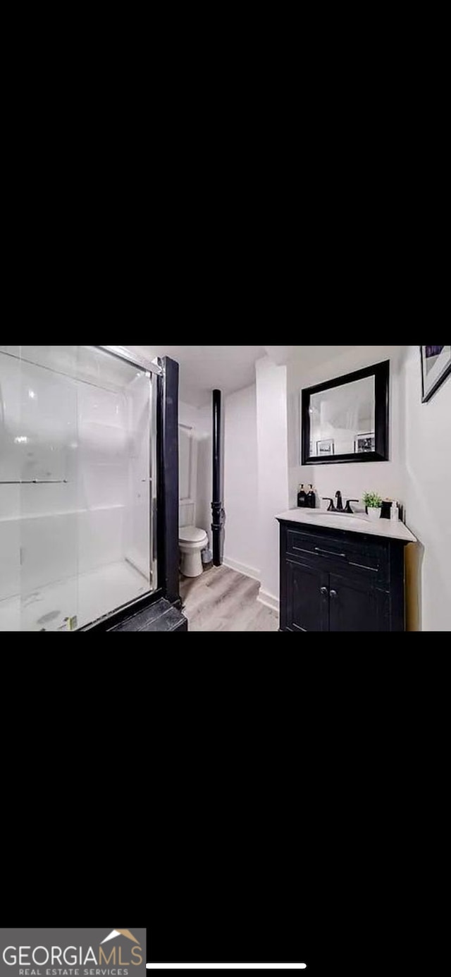 bathroom with vanity, hardwood / wood-style floors, a shower with shower door, and toilet