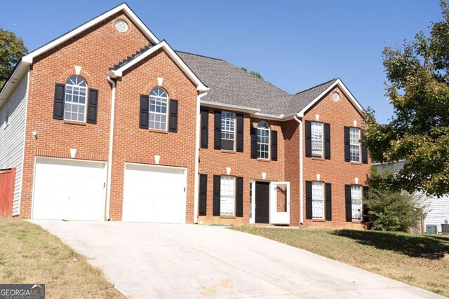 view of front of property featuring central AC, a front yard, and a garage