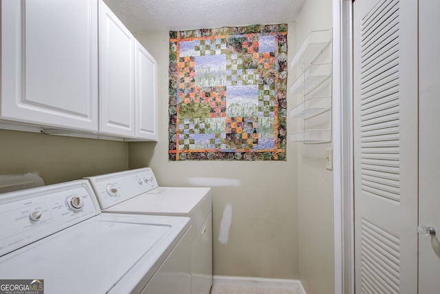 laundry room with a textured ceiling, washing machine and dryer, and cabinets