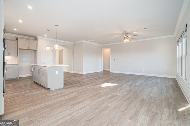 kitchen with gray cabinetry, a center island with sink, hanging light fixtures, and light wood-type flooring