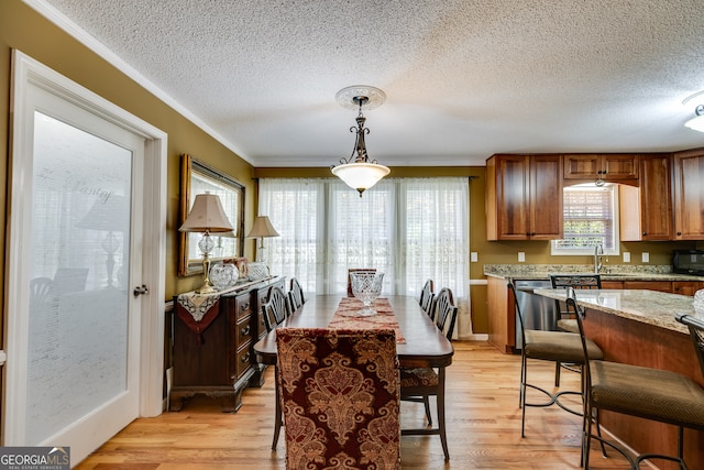 dining space with ornamental molding, a textured ceiling, and light wood-type flooring