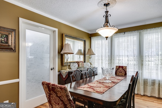 dining space with crown molding, a textured ceiling, and light wood-type flooring