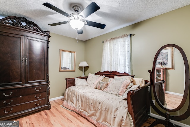 bedroom featuring a textured ceiling, light wood-type flooring, and ceiling fan