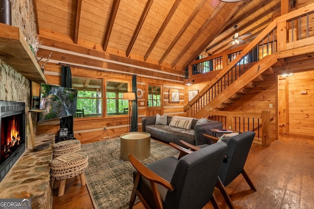 living room featuring wood ceiling, hardwood / wood-style floors, wooden walls, a fireplace, and beamed ceiling