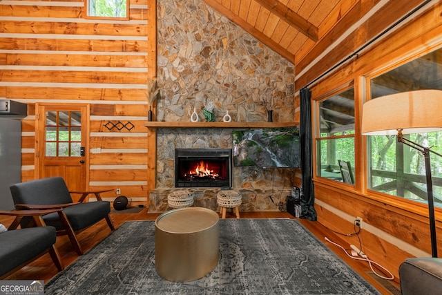 living area featuring hardwood / wood-style floors, high vaulted ceiling, a stone fireplace, wooden ceiling, and beamed ceiling