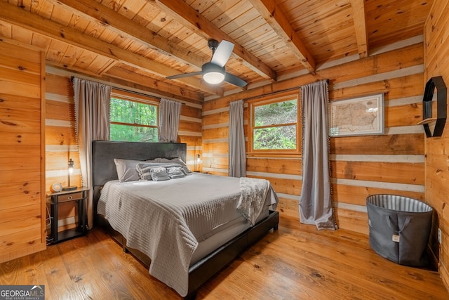 bedroom with wood walls, wooden ceiling, beamed ceiling, ceiling fan, and hardwood / wood-style floors