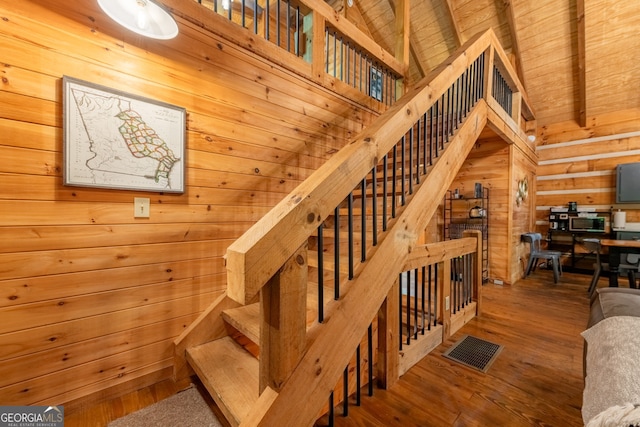 staircase featuring high vaulted ceiling, hardwood / wood-style flooring, wooden ceiling, and wood walls