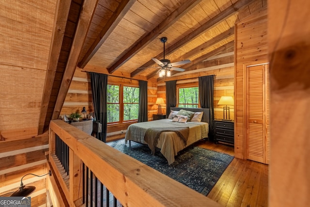 bedroom with hardwood / wood-style floors, wooden walls, vaulted ceiling with beams, ceiling fan, and wood ceiling