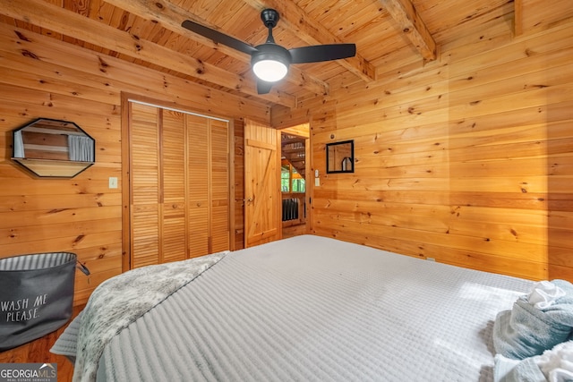 bedroom with a closet, wood ceiling, beam ceiling, and wood walls