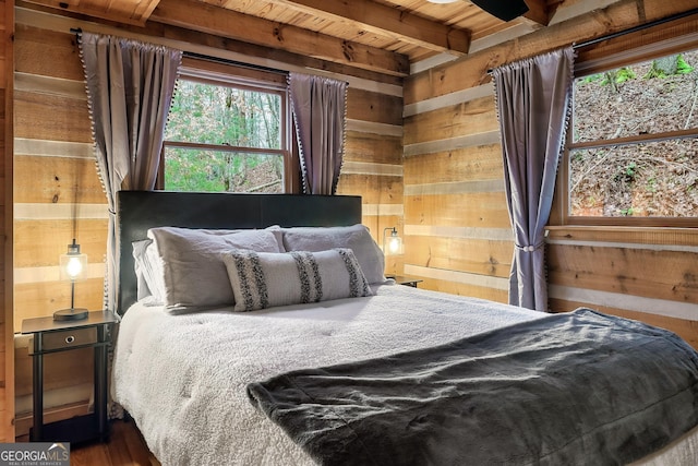 bedroom with beam ceiling, wooden ceiling, and wooden walls