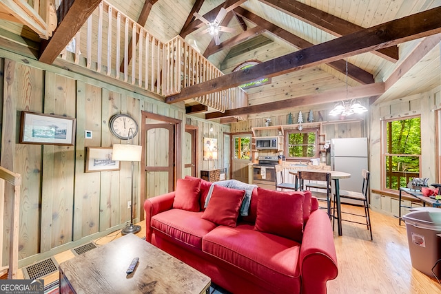 living room featuring ceiling fan with notable chandelier, beamed ceiling, wooden walls, high vaulted ceiling, and light hardwood / wood-style flooring