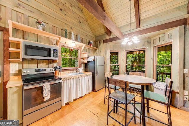 kitchen featuring lofted ceiling with beams, decorative light fixtures, stainless steel appliances, and plenty of natural light