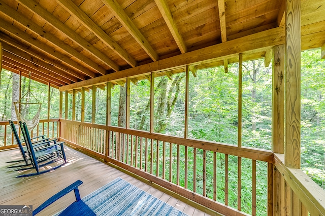 unfurnished sunroom featuring beam ceiling, a healthy amount of sunlight, and wooden ceiling