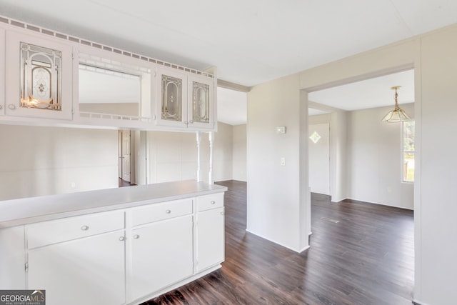 kitchen featuring white cabinets, decorative light fixtures, and dark wood-type flooring