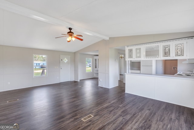 unfurnished living room featuring vaulted ceiling with beams, plenty of natural light, dark hardwood / wood-style floors, and ceiling fan