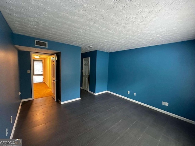 spare room with a textured ceiling and dark hardwood / wood-style flooring