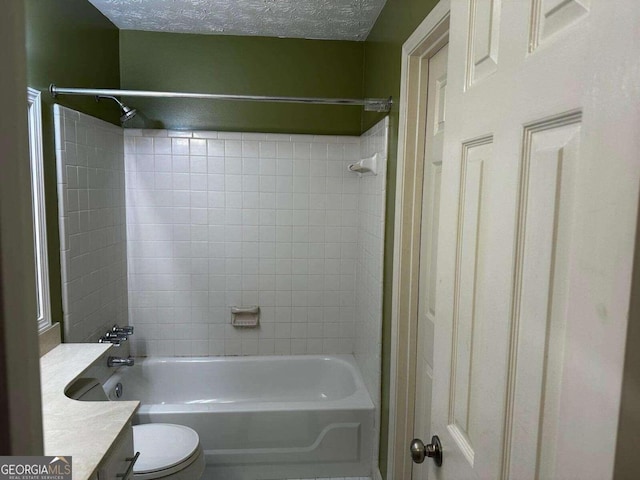 full bathroom featuring vanity, toilet, a textured ceiling, and tiled shower / bath