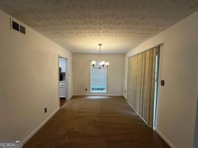 corridor featuring a textured ceiling, a chandelier, and dark colored carpet