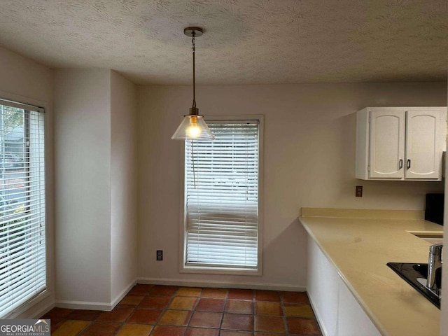 unfurnished dining area with dark tile patterned floors and a textured ceiling