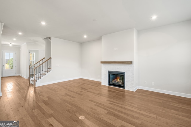 unfurnished living room featuring light hardwood / wood-style floors and a brick fireplace