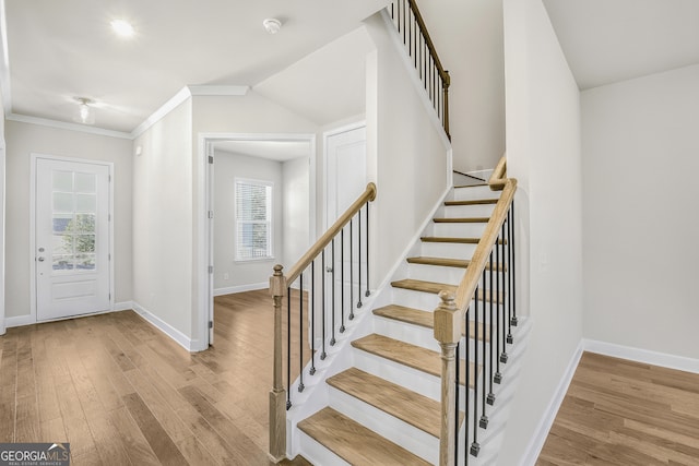 foyer featuring light hardwood / wood-style floors, vaulted ceiling, and ornamental molding