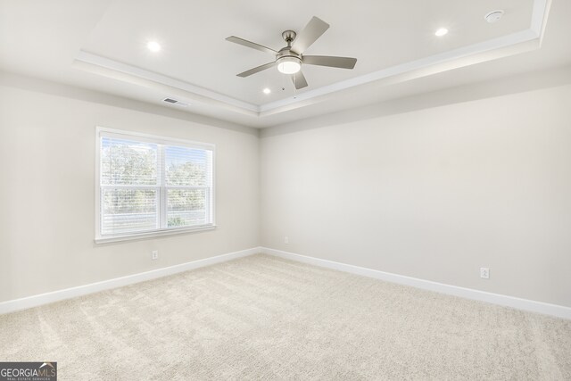 carpeted empty room with a tray ceiling and ceiling fan