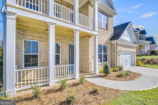 view of exterior entry with covered porch, a garage, and a balcony