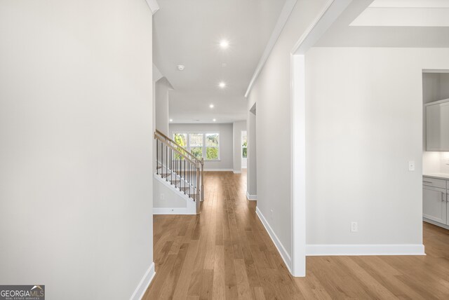 hallway featuring light wood-type flooring and crown molding