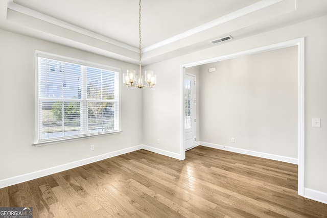 unfurnished room with a notable chandelier, wood-type flooring, and a tray ceiling