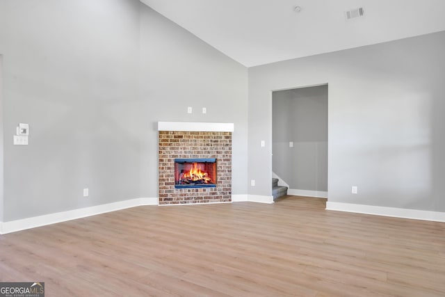 417 Lakeview Pl, Macon, GA 31211 - unfurnished living room featuring high vaulted ceiling, a tiled fireplace, light wood finished floors, stairs, and baseboards