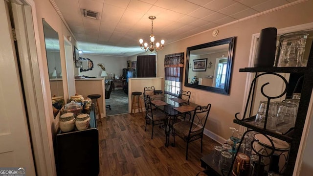 dining area featuring an inviting chandelier, crown molding, and hardwood / wood-style flooring