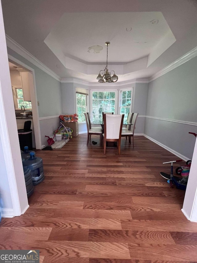 dining room featuring crown molding, a tray ceiling, a chandelier, and wood-type flooring