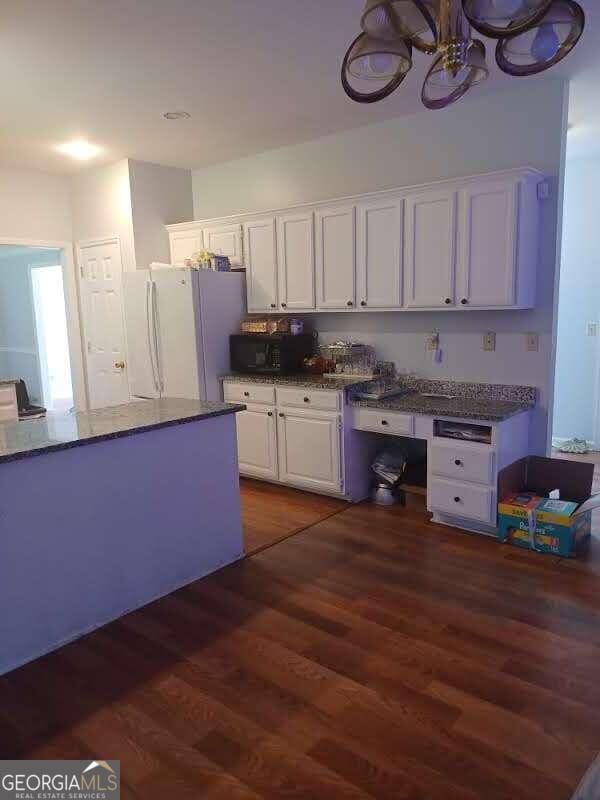 kitchen featuring dark hardwood / wood-style flooring, an inviting chandelier, white cabinetry, and white refrigerator