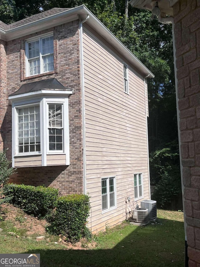 view of side of property featuring cooling unit and a lawn