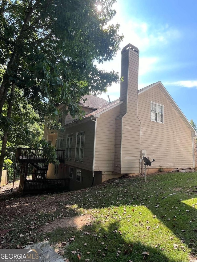 view of property exterior with a yard and a wooden deck