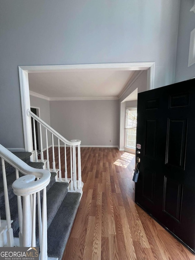 entryway with ornamental molding and wood-type flooring