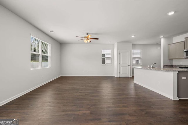 unfurnished living room with dark hardwood / wood-style floors, sink, and ceiling fan