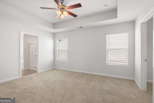 carpeted spare room featuring a raised ceiling and ceiling fan