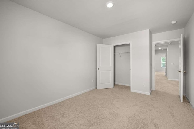 unfurnished bedroom featuring light carpet and a closet