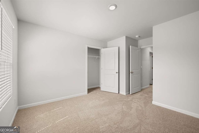 unfurnished bedroom featuring light carpet and a closet